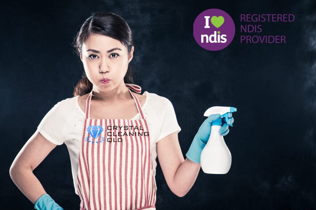 A determined woman cleaning for NDIS Registered Provider Crystal Cleaning QLD in Brisbane and Gold Coast, holding a spray bottle and wearing a logo-branded apron against a dark background.