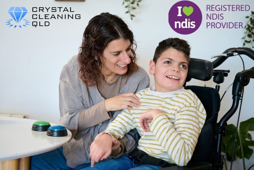 A smiling mother supporting her happy young son in a wheelchair at home, representing supportive home care and plan goals by NDIS Registered Provider Crystal Cleaning QLD across Brisbane and Gold Coast.