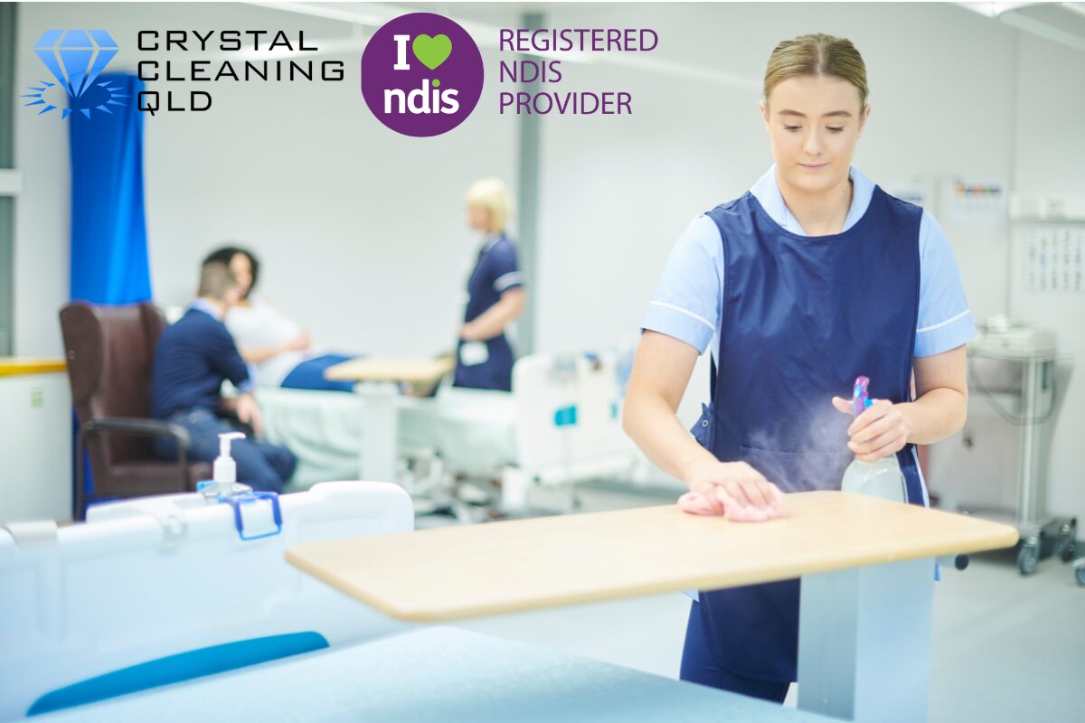 A professional female cleaner spraying and wiping down a mobile overbed table in a healthcare facility for safe infection control, representing NDIS Registered Provider Crystal Cleaning QLD across Brisbane and Gold Coast.