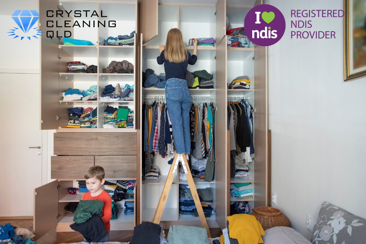 A professional woman from Crystal Cleaning QLD organising a large wardrobe and sorting clothes on a step ladder, showcasing domestic care and NDIS house cleaning supports in a tidy Brisbane home.
